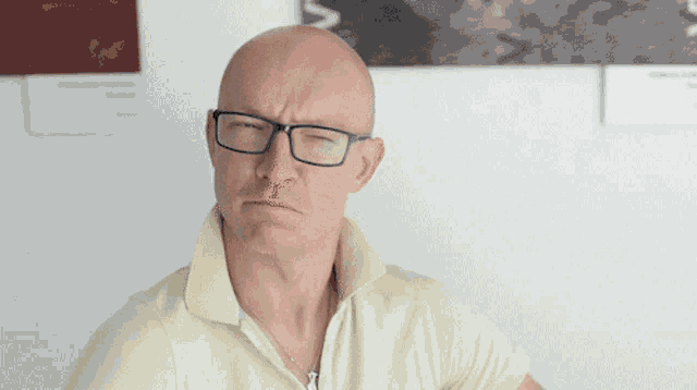 a bald man wearing glasses and a yellow shirt has the word nope written in black letters
