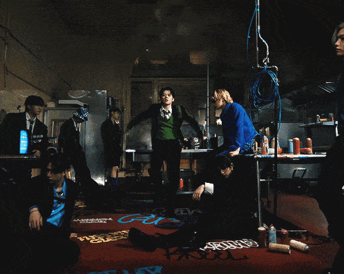 a man wearing a black jacket and a necklace is dancing in a dark room