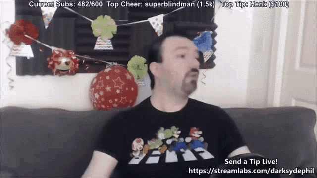 a man is sitting on a couch in front of balloons and a banner that says current subs 482/600