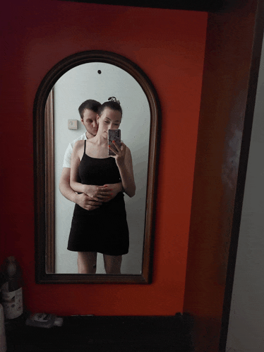 a man and a woman are taking a picture in a mirror