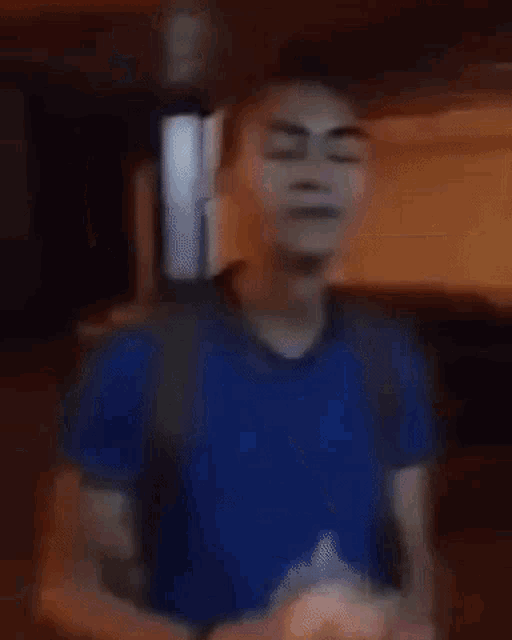 a man in a blue shirt is holding a piece of food in his hands .