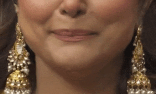 a close up of a woman 's face wearing gold and pearl earrings