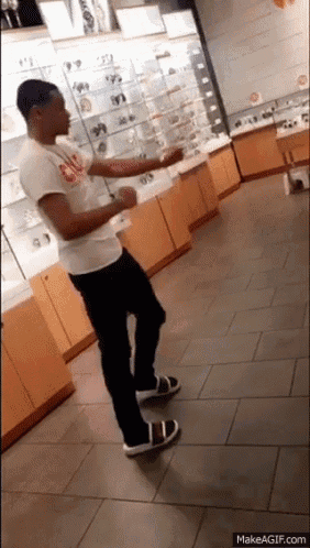 a man is dancing in a store with a makeagif.com link