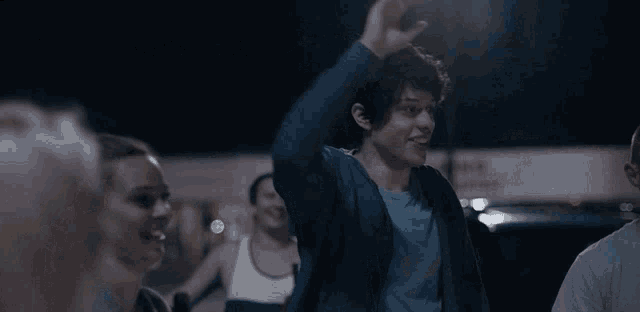 a man in a blue jacket is dancing in a crowd of people .