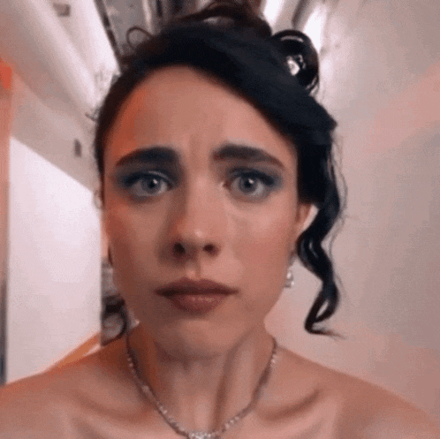 a woman wearing a necklace and earrings is making a face .