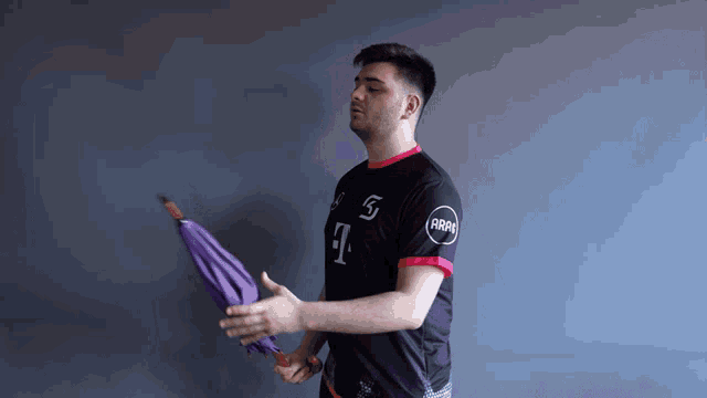 a man holding a purple umbrella and wearing a shirt that says t-mobile on it