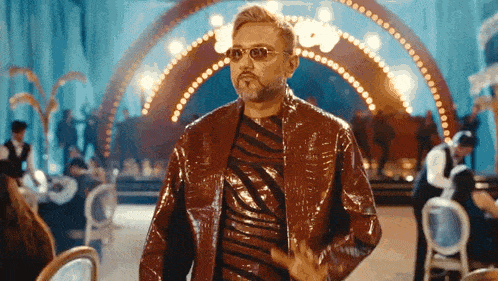 a man in a red jacket and sunglasses is standing in a room