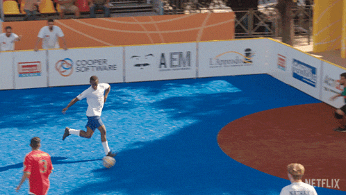 a man kicks a soccer ball in front of a fence that says aem on it