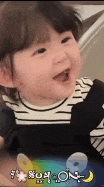 a baby is smiling in front of a sign that says ' sun moon ' on it