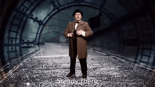 a man in a top hat stands in front of a large clock and says steady there