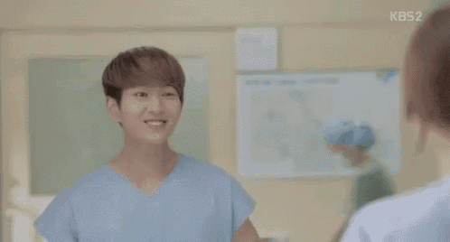 a man and a woman are standing next to each other in a hospital room and smiling at each other .