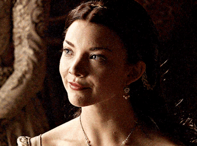a woman wearing a necklace and earrings is looking to the side