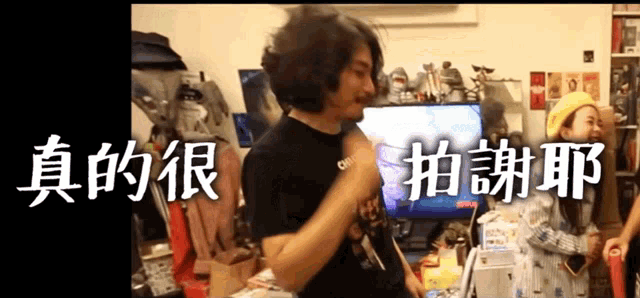 a man stands in front of a television with chinese writing on it
