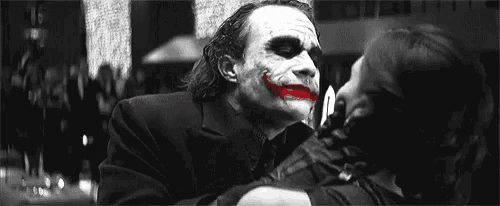a black and white photo of the joker kissing a woman on the cheek .