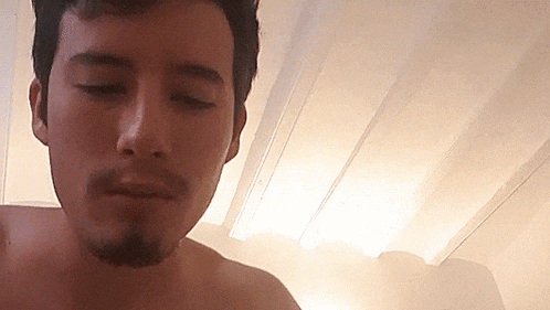 a shirtless man with a beard is looking down at something