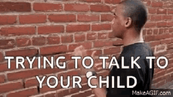a man is standing in front of a brick wall talking to a child .