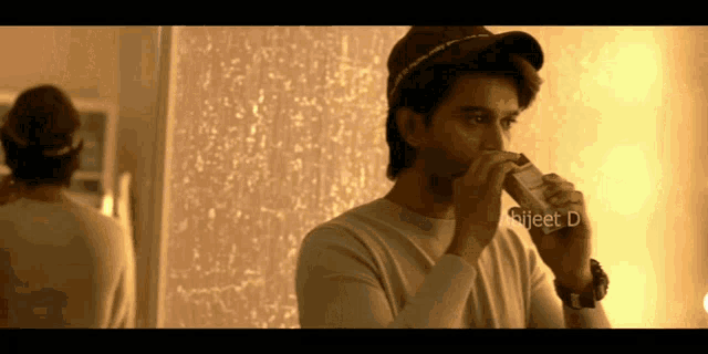 a man in a baseball cap is drinking from a bottle with the name bijeet d written on it