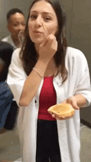a woman in a white coat is holding a piece of food in her hand .