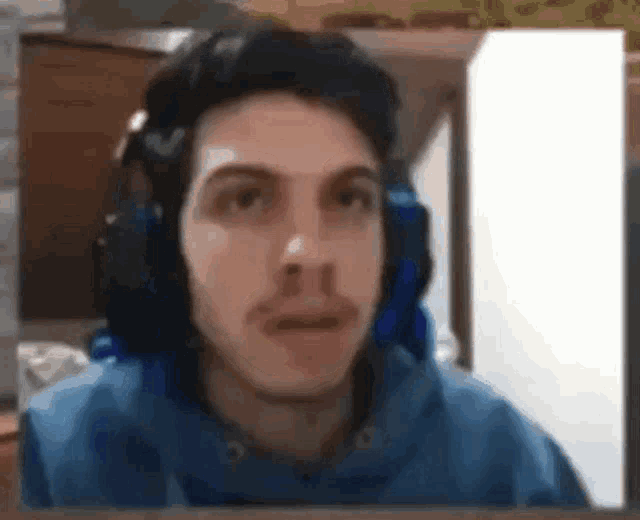 a man wearing headphones and a blue hoodie looks at the camera .