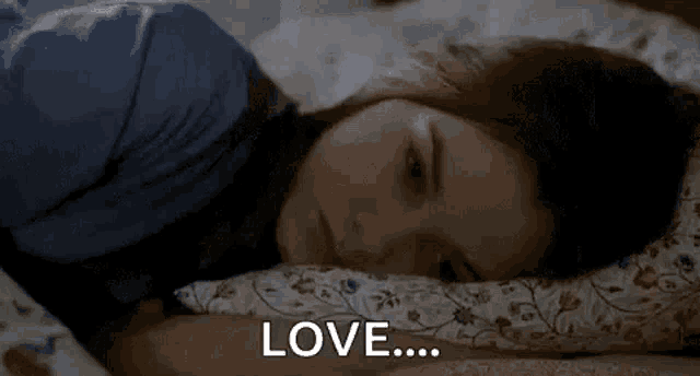 a woman is laying in bed with her head on a pillow and the words `` love '' written on the bottom .