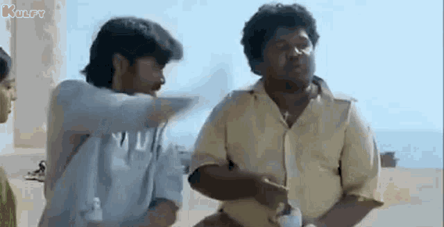 a group of men are standing next to each other on a beach and talking to each other .