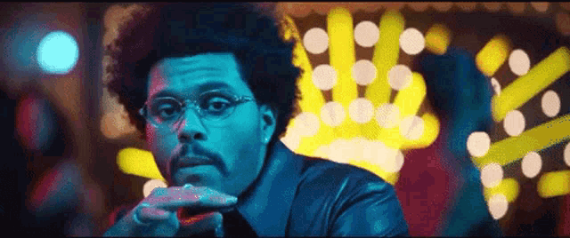 a man wearing glasses and a leather jacket is sitting in front of a casino sign .