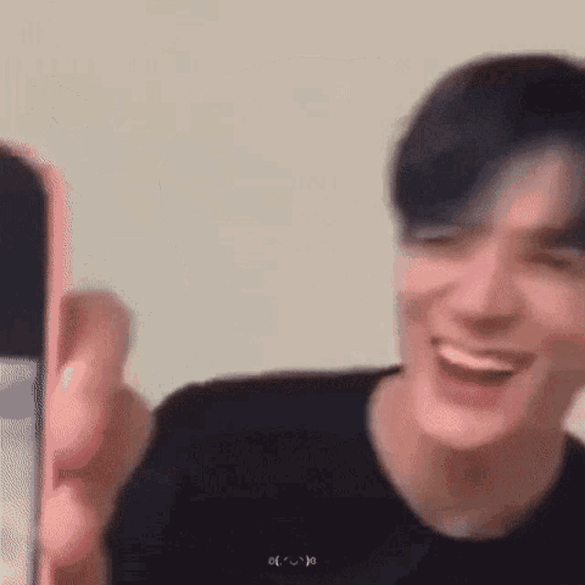 a man is laughing while holding a pink cell phone .