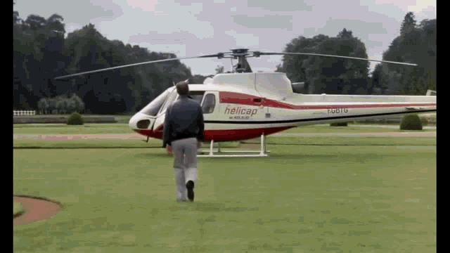 a man runs towards a helicopter that says helicap on the side