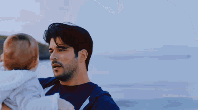 a man is holding a baby in his arms on a beach .