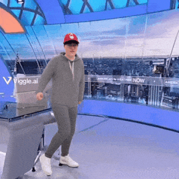 a man wearing a red hat and glasses is dancing in front of a sign that says america 's weather now
