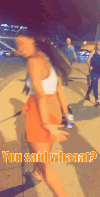 a woman in a white tank top and orange skirt is standing on a sidewalk with the words " you said whaata " above her