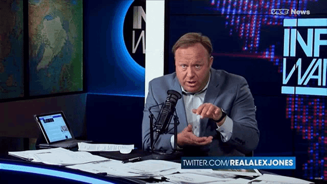 alex jones is talking into a microphone in front of a twitter.com logo