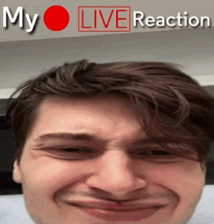 a man is making a funny face in front of a sign that says ' my live reaction '