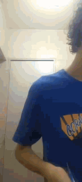 a man in a blue shirt is brushing his teeth in a bathroom with a toothbrush .