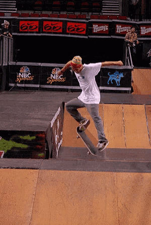 a skateboarder is doing a trick on a ramp with a nbc sports sign in the background