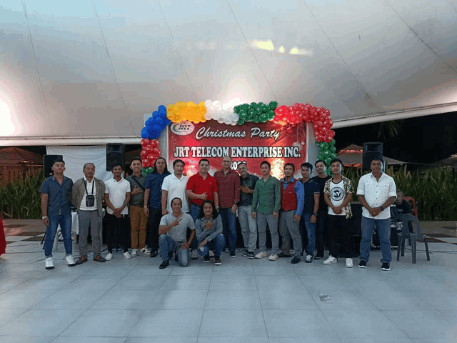 a group of people standing in front of a christmas party sign