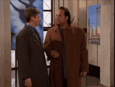 two men standing next to each other in front of a painting of a city