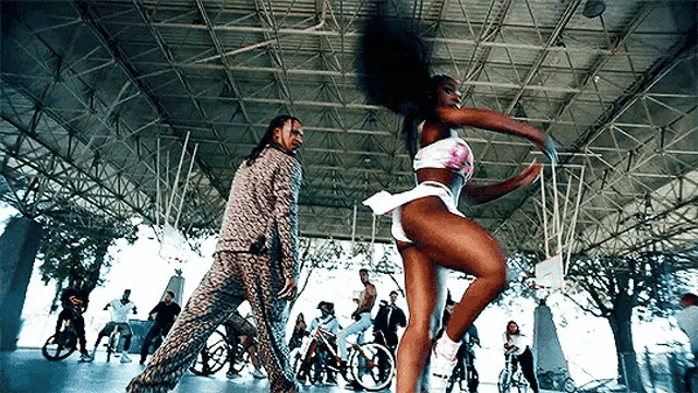 a man and a woman are dancing in front of a basketball hoop in a gym .
