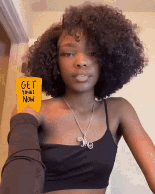 a woman with curly hair is wearing a black tank top