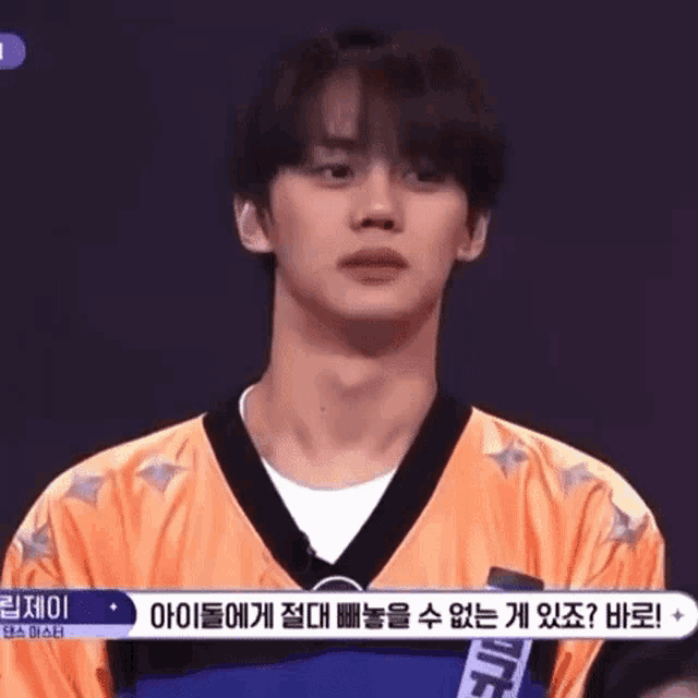 a young man in an orange and black jersey is standing in front of a crowd .