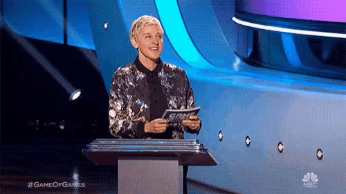 ellen degeneres stands at a podium holding a piece of paper that says game of games on the bottom