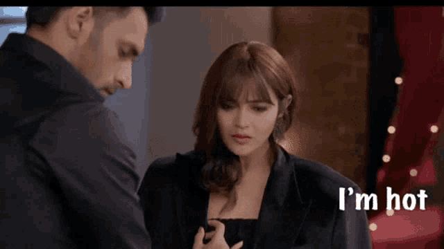 a man and a woman are standing next to each other and the woman is looking at the man .
