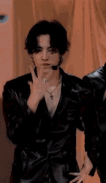 a man in a black leather jacket is dancing on a stage .