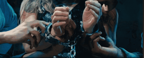 a woman is handcuffed to a man 's arm in a dark room