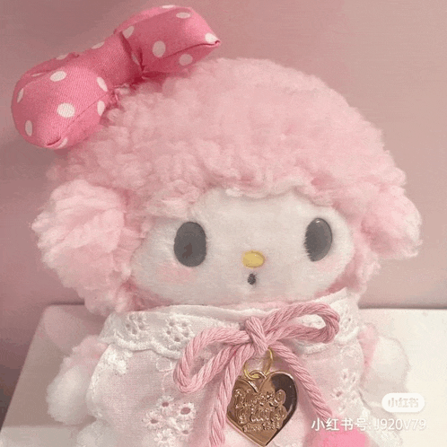a pink stuffed animal with a bow on its head is sitting on a table ..