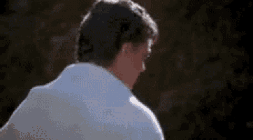 a man in a white shirt is standing in front of a dark background .