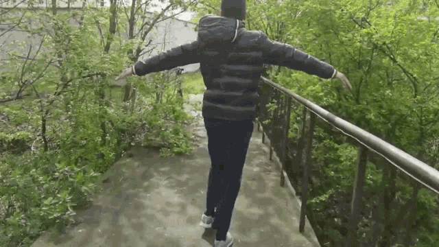 a person with their arms outstretched is walking across a bridge