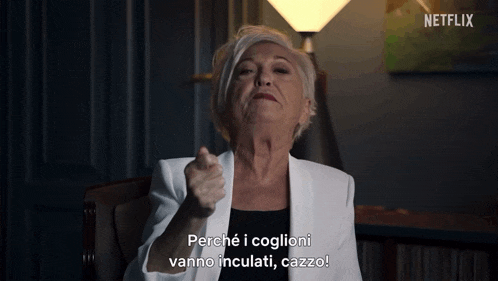 a woman in a white jacket is pointing at the camera and says " perché i coglioni vanno inculati cazzo "