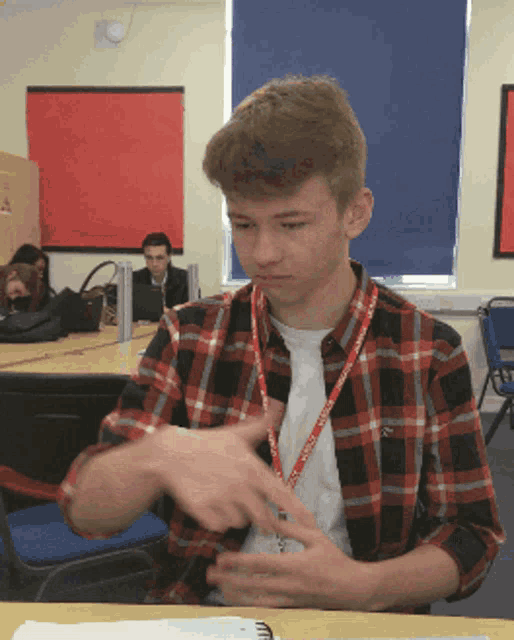 a young man wearing a lanyard that says ' oxford ' on it sits at a desk