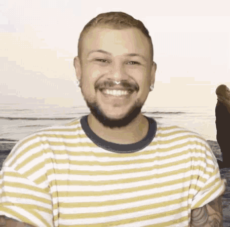 a man wearing a yellow and white striped shirt smiles for the camera